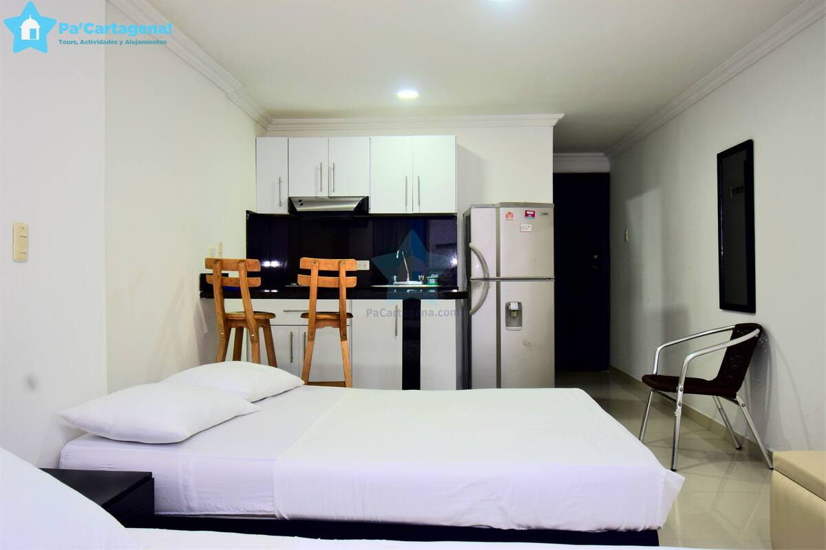 A hotel room with a bed, a desk with two chairs, a refrigerator, and a microwave.