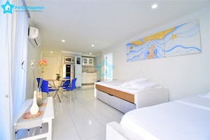 Une chambre d’hôtel comprenant un lit, un bureau avec une chaise, une table à manger avec des chaises et un coin cuisine.