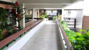 Un couloir au sol carrelé, agrémenté de plantes en pot et d’un banc en bois.