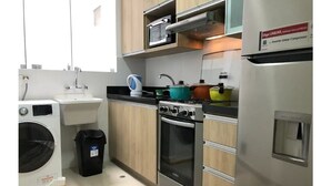 Une cuisine de taille réduite équipée d’un lave-linge, d’un évier, d’une cuisinière et d’un réfrigérateur.