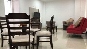 Un salon moderne avec des chaises en bois foncé, un canapé rouge et un téléviseur à écran plat.