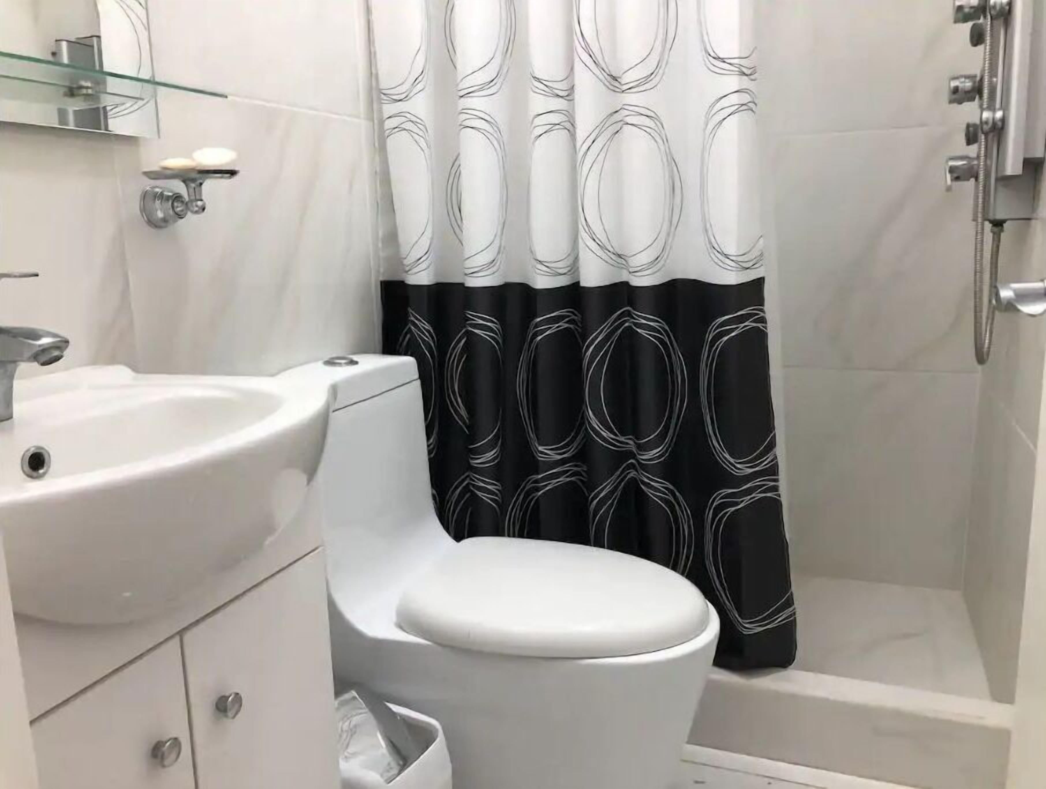 A bathroom with a white toilet, a white sink, and a shower area.