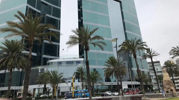 Un hôtel moderne doté de deux tours imposantes, avec des palmiers au premier plan et un ciel dégagé.