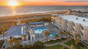 Ein Resort mit Pool, Strandzugang und Blick auf den Sonnenuntergang über dem Meer.