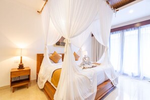 A bedroom with a four-poster bed, a bedside table with a lamp, and a window with curtains. - Villa Sonia Bisma (Ubud)