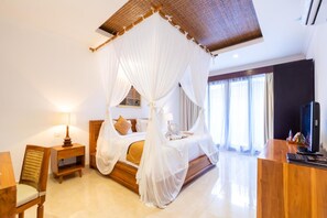 A bedroom with a canopy bed, a wooden desk, a chair, and a television. - Villa Sonia Bisma (Ubud)