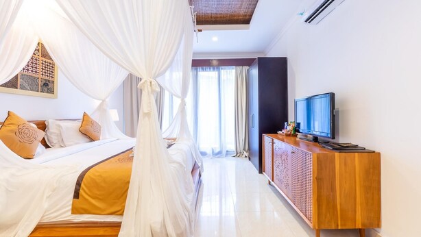 Una habitación de hotel con cama, televisor, un aparador de madera y una ventana con cortinas.