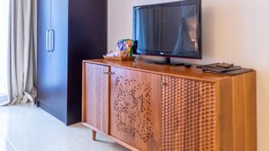 Habitación moderna con una televisión de pantalla plana sobre un mueble de madera, un armario y un equipo de aire acondicionado.