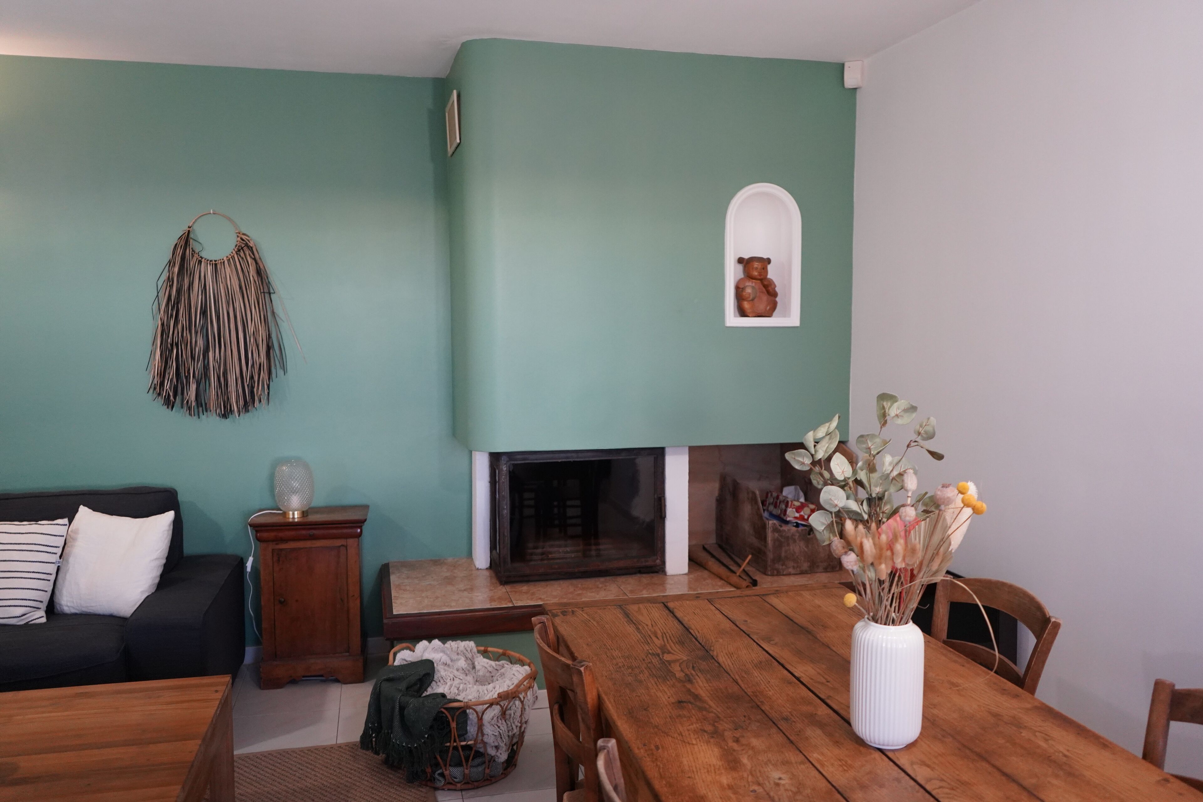 A living room with teal walls, a fireplace, a wooden dining table, and a sofa.