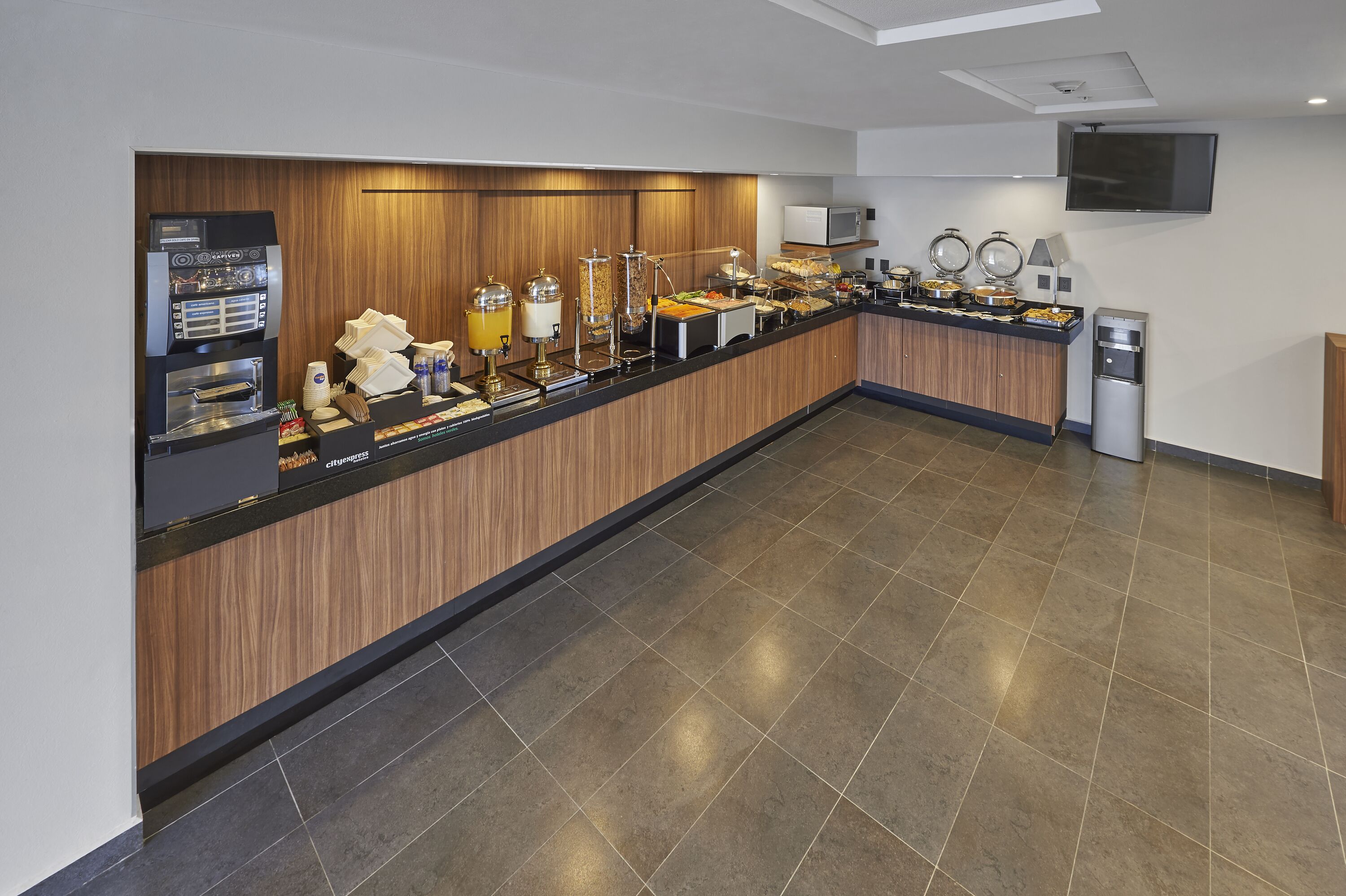 A buffet setup with a coffee machine, juice dispensers, and various food items.
