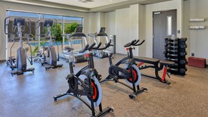 Un gimnasio con bicicletas estáticas, cintas de correr y una banca.