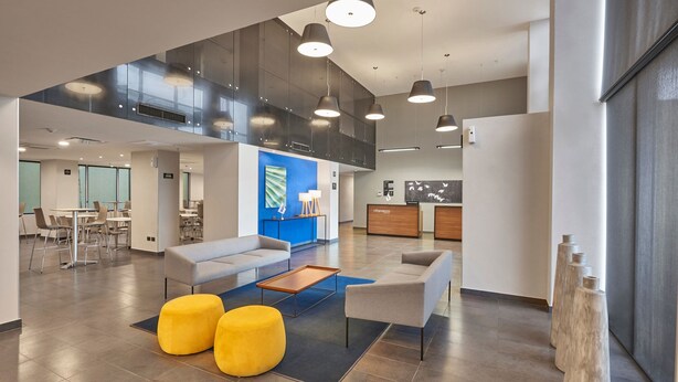 Un hall amplio con techo alto, mobiliario moderno y un área de estar central.
