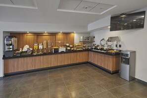 A modern kitchen with a wooden countertop, a coffee machine, a refrigerator, and a microwave.