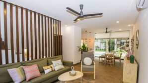 Un salon moderne avec un canapé d’angle, une petite table ronde et un ventilateur de plafond.
