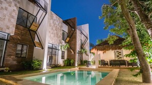 Un bâtiment moderne doté d’une piscine, d’un espace extérieur aménagé et d’un jardin paysager aux allures tropicales.