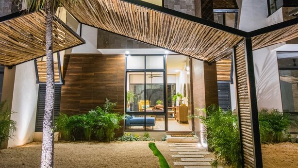 Une maison moderne dotée d’un patio couvert, d’un escalier et d’une entrée bien éclairée.