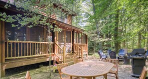 A wooden cabin with a deck, surrounded by trees. - Wander Inn - Updated Log Cabin near shared beach (Saugatuck)