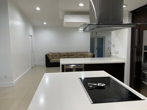 Modern kitchen with a central island, induction cooktop, and stainless steel sink.