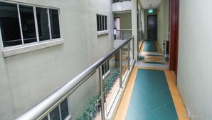Un edificio de varios niveles con un pasillo central, barandas de vidrio y un piso cubierto de baldosas verdes.