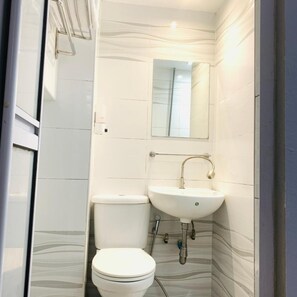 A small, compact bathroom with a toilet, sink, and mirror.