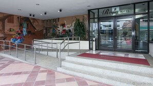 Entrada de un hotel con un mural, una escalera y una puerta de cristal con el rótulo 'Regin Hotel'.