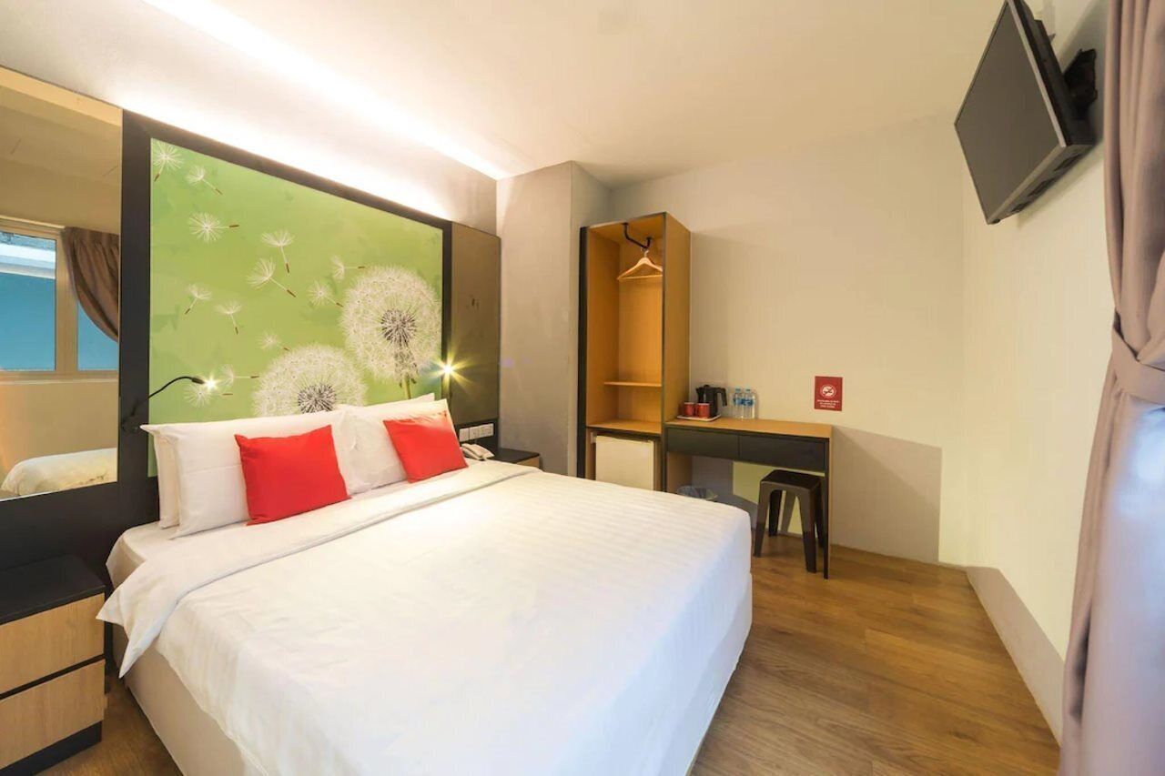 Una habitación de hotel con cama, escritorio, silla, televisor y armario.
