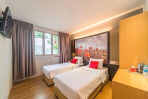 A hotel room with two beds, a wooden desk, a painting on the wall, and a window with curtains.