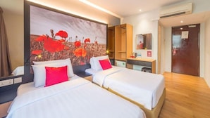 Una habitación de hotel con dos camas, un cuadro grande de flores rojas, un escritorio de madera y un espejo.