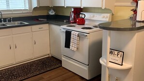 A kitchen with white cabinets, a stove, a red kettle, and a Wi-Fi sign. -  EZ - GO Lodging 3.7 mi Green Pond Landing(Lake Hartwell) Clemson Univ 15 mil. (Anderson)