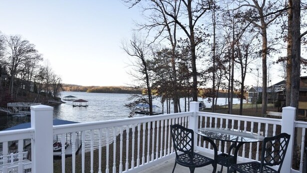 Une terrasse avec une table et des chaises donnant sur un lac où l’on peut voir des bateaux.