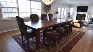 Un vaste espace dédié à la salle à manger, avec une grande table en bois, de nombreuses chaises et un tapis à motifs.