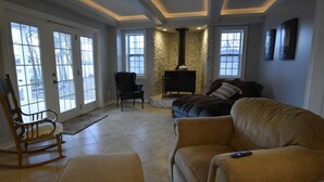 Un salon avec une cheminée, un fauteuil à bascule et un canapé.