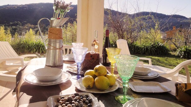 An outdoor dining setup with a table set for two, featuring a bottle of wine, a pitcher, lemons, and olives. - 2 198 / 5 000
Cozy cottage with private garden and terrace – peaceful setting (Le Bar-sur-Loup)