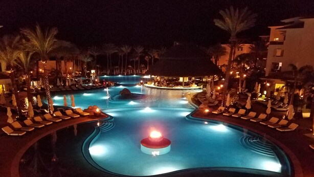 A nighttime view of a hotel pool area with lounge chairs and palm trees. - 2 Bedroom Serenity Pool View (San José del Cabo)