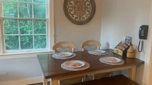Uma mesa de jantar com quatro cadeiras, um objeto decorativo na parede e um telefone fixado na parede.