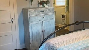Quarto com cama, cômoda e janela com persianas.