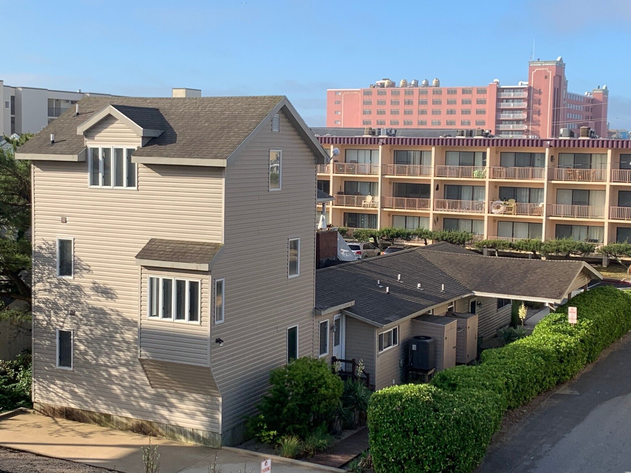 A residential area with detached houses and a multi-story building in the background.