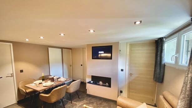 Ett modernt hotellrum med en matplats, en platt-TV, en öppen spis och en soffa.