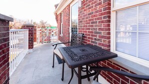 Eine Terrasse mit Tisch und Stühlen, eine Backsteinmauer und ein Fenster.
