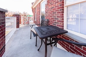 Eine Terrasse mit Tisch und Stühlen, eine Backsteinmauer und ein Fenster.