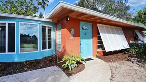 A two-story house with a blue garage and a red main building. - Old Florida Key West Cottage w/ river access (Jensen Beach)