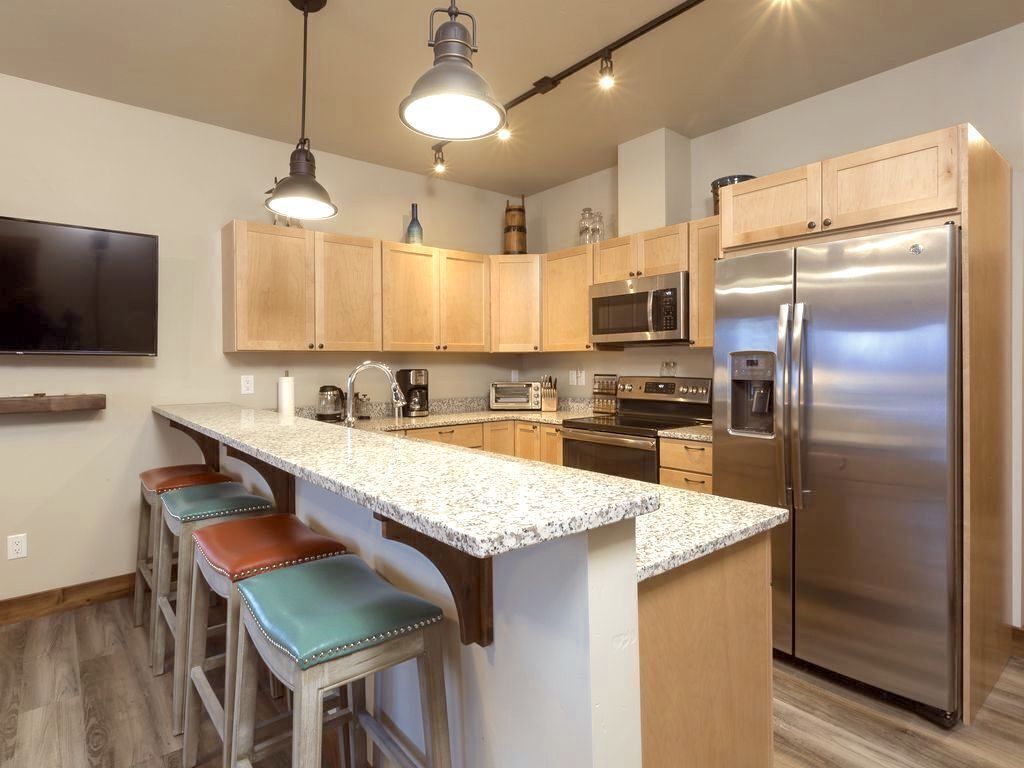 A modern kitchen with wooden cabinets, stainless steel appliances, and a granite countertop.