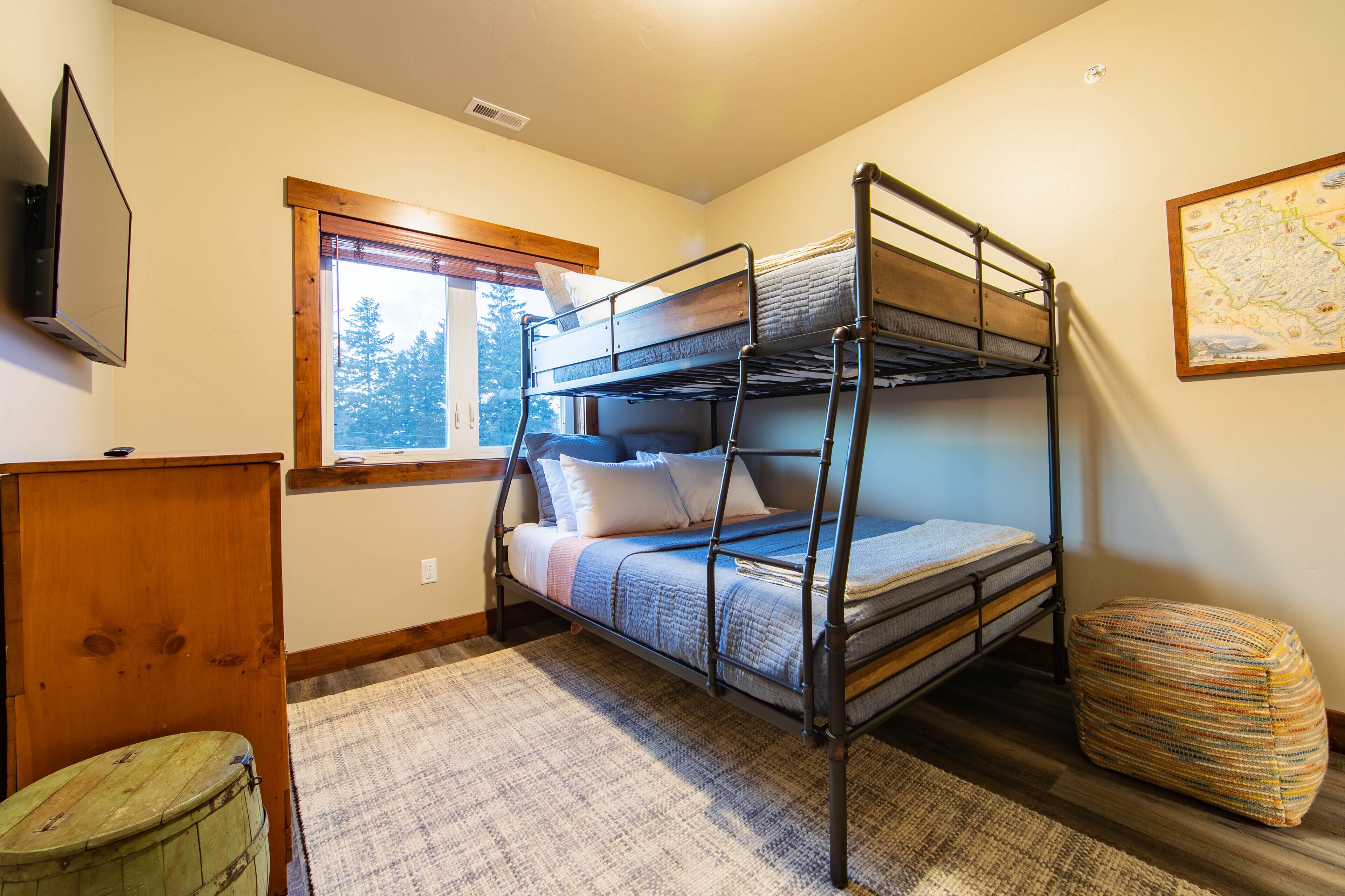 A bunk bed room with a window, a map on the wall, and a small wooden desk.