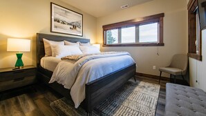 A bedroom with a bed, a nightstand, a chair, a window, and a framed picture on the wall. - Beautiful 3-bed/2-bath Condo Looking Into Glacier National Park! (Columbia Falls)