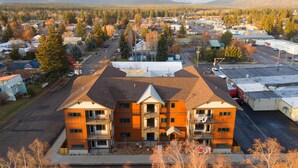 A multi-story building with a central courtyard and a parking lot in the foreground. - Beautiful 3-bed/2-bath Condo Looking Into Glacier National Park! (Columbia Falls)