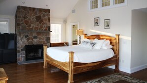 Ein Schlafzimmer mit Kamin aus Stein, einem hölzernen Bett und einem Deckenventilator.