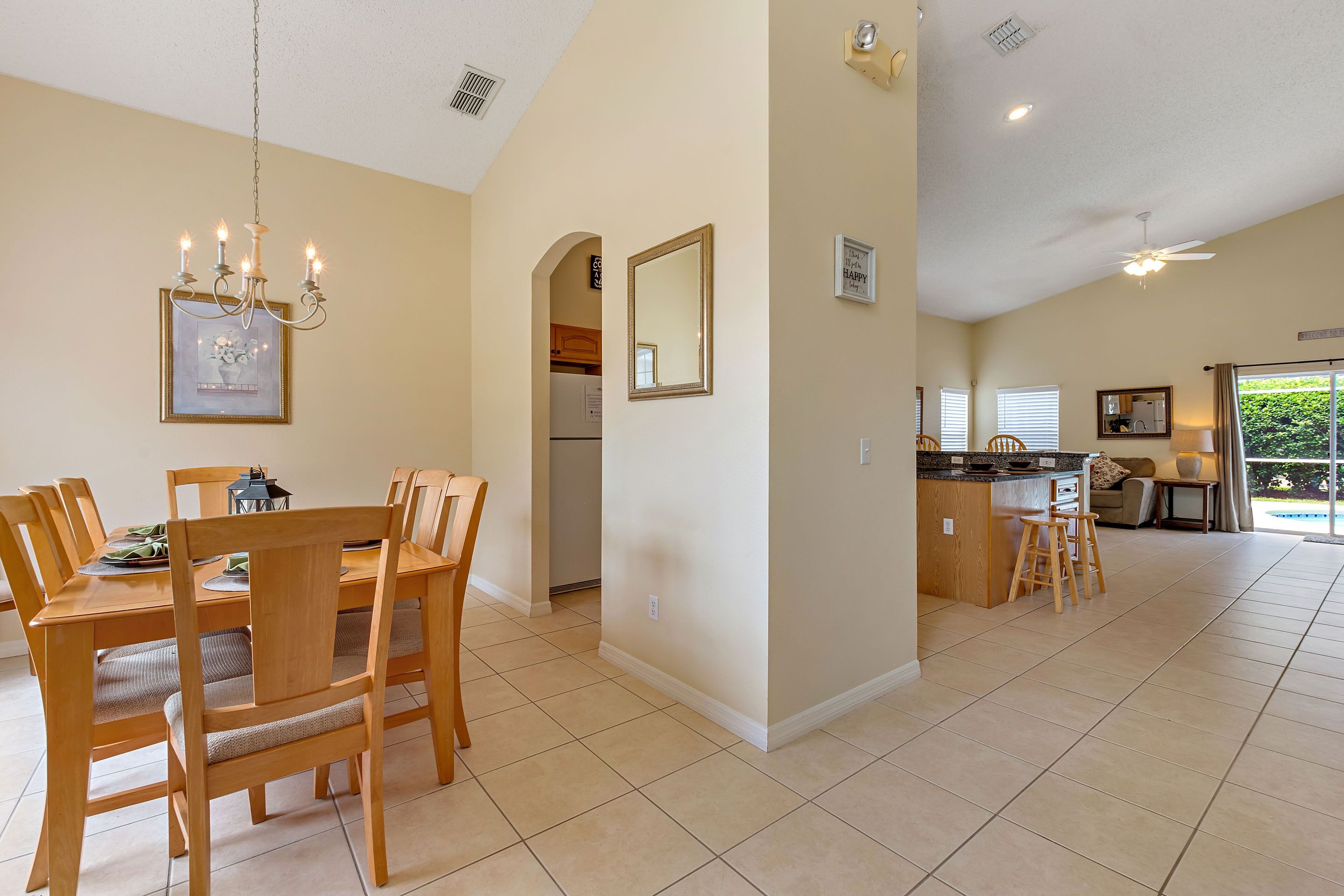 A spacious kitchen with a dining area, wooden furniture, and a chandelier.