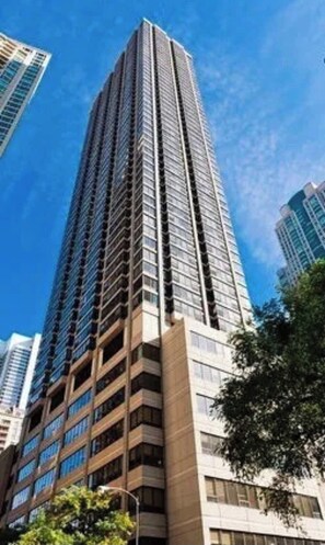 A tall, modern skyscraper with a glass facade and multiple balconies. - Luxury 1BR Condo – Views, Comfort, & Style (Chicago)