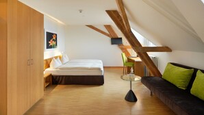 Un dormitorio tipo loft moderno con suelo de madera, una cama, un sofá y una mesa de centro de vidrio.