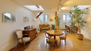 Una habitación amplia con una mesa de comedor de madera, varias sillas, un sofá y una planta grande en maceta.